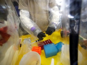 A lab technician works in a mobile lab as Canada's Federal Minister of Health Rona Ambrose (not pictured) tours the National Microbiology Lab in Winnipeg, Manitoba, November 3, 2014. REUTERS/Lyle Stafford (CANADA - Tags: HEALTH POLITICS)