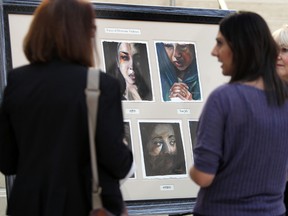 A group of ladies looks at artwork called Faces of Domestic Violence during the launch of Family Violence Prevention Month at City Hall in Edmonton, Alberta on Monday, November 3, 2014. Perry Mah/Edmonton Sun
