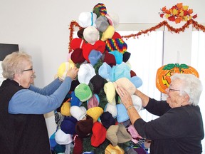 Florence Sokvitne, left, and Betty Smith, organizers of the annual Christmas Tree for the Needy, hang up a couple of toques on the tree Oct. 28 at the Vulcan Senior Centre. With 600 items already donated and more expected, the goal of 1,000 is already almost reached. Donated items are distributed locally to groups like the Vulcan and District Family and Community Support Services, and any leftover donations are also sent to groups like the Mustard Seed in Calgary and the Harbour House in Lethbridge. Simon Ducatel Vulcan Advocate