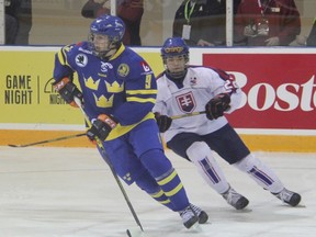 Linus Hogberg of Sweden protects the puck from Slovakian forward Jakub Lacka during World Under-17 Hockey Challenge preliminary play in Lambton Shores Tuesday afternoon. Sweden scored early and often, collecting its first win of the tournament. (TERRY BRIDGE/THE OBSERVER)