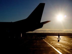 An attendant and a Flair Airlines Boeing 737-400 charter airplane are silhouetted on the Grande Prairie Airport tarmac on Tuesday, Nov. 4, 2014. TOM BATEMAN/DAILY HERALD TRIBUNE/QMI AGENCY