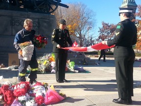 Military groups and city workers dismantle the tributes to slain soldier Cpl. Nathan Cirillo Sunday in Ottawa to ready the National War Memorial for Remembrance Day. Non-floral mementos were sent to the families of Cirillo, who was shot while on guard at the war memorial on Oct. 22 and Warrant Officer Patrice Vincent, who was run down by a radicalized man in St-Jean-sur-Richelieu, Que. on Oct. 20. The bouquets were delivered to the homes of veterans. (photo by Danielle Bell/QMI Agency)