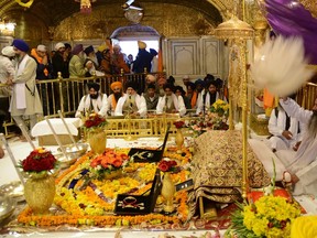 Indian Sikh head priest Sukhjinder Singh (R) sits behind the Sikh Holy Book during a "Jalau," a splendour show of Sikhism's symbolic items, inside the Sikh Shrine Golden Temple in Amritsar on Nov. 17, 2013. The Jalau took place on the occasion of the 544th birthday of Sri Guru Nanak Dev. Guru Nanak was the founder of the religion of Sikhism and the first of ten Sikh Gurus.  (AFP PHOTO)