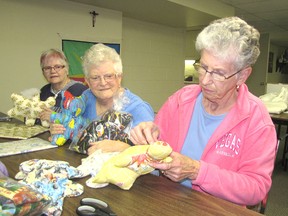 Marguerite Santarossa, centre, watches Jan Attewell, right, stitch together a Burden Bear in St. Mary's Catholic Church in Blenheim. Since May, the “Burden Bear Ladies,” led by Santarossa, have been getting together on Monday mornings to make the bears that are given to comfort people who are facing a serious illness. Also pictured is Roberta Summerfield.