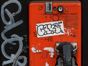 A telephone booth is seen covered in graffiti, including a "Gloria" tag, at 104 Street and 82 Avenue in Edmonton, Alta., on Friday, Sept. 26, 2014. Ian Kucerak/Edmonton Sun