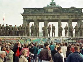 East Berlin border guards stand atop the Berlin Wall in front of the Brandenburg Gate in Berlin in this file picture taken November 11, 1989.   REUTERS/Staff/Files