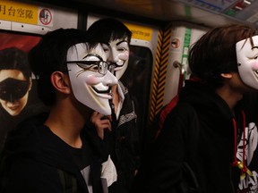 Pro-democracy protesters wearing Guy Fawkes masks stand in front of an advertisement as they take a subway train to a protest site occupied by them as part of the Occupy Central civil disobedience movement in Hong Kong November 5, 2014, the day marking Guy Fawkes Night.  REUTERS/Bobby Yip
