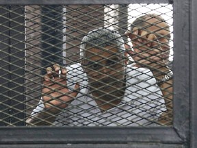 Mohamed Fahmy stands behind bars as he waits to listen the ruling at a court in Cairo June 23, 2014. 

REUTERS/Asmaa Waguih