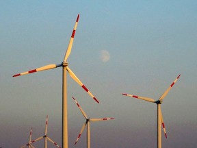 The moon is pictured behind power-generating wind turbines from a wind farm near the village of Ludwigsburg, northern Germany October 5, 2014. REUTERS/Fabrizio Bensch