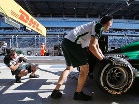 Mechanics lift the car of Caterham Formula One driver Marcus Ericsson during the second free practice session of the Russian Grand Prix in the Sochi Autodrom October 10, 2014. (REUTERS/Maxim Shemetov)