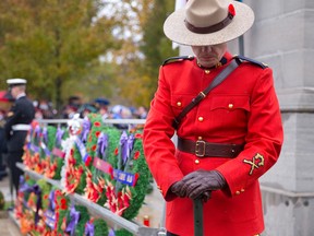 A RCMP officer stands with his head bowed at the corner of the Victoria Park cenotaph before the Remembrance Day ceremony in London, Ont. on Monday November 11, 2013. (CRAIG GLOVER, The London Free Press)