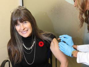 MPP Sophie Kiwala, left, gets her flu shot from Shama Acharya, owner of the Shoppers Drug Mart at Princess and Bagot streets, as she promotes the availability of flu shots at local pharmacies. FRI., NOV. 7, 2014 KINGSTON, ONT. MICHAEL LEA THE WHIG STANDARD QMI AGENCY