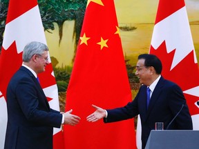 Canada's Prime Minister Stephen Harper (L) shakes hands with China's Premier Li Keqiang, in front of Canadian and Chinese (C) national flags, during a joint news conference at the Great Hall of the People in Beijing November 8, 2014. REUTERS/Petar Kujundzic