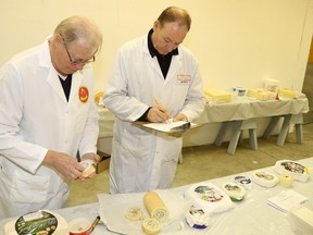 Joseph Leupi (left) and  Evan Matte judge several samples of speciality cheeses at the the Empire Cheese Show, held in Belleville over the weekend. Jason Miller/ The Intelligencer