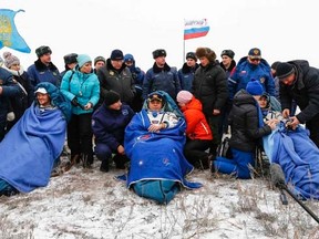 The International Space Station (ISS) crew of Alexander Gerst of Germany (L-R), Maxim Surayev of Russia and Reid Wiseman of the U.S. rest after landing in a remote area near the town of Arkalyk in northern Kazakhstan, November 10, 2014. REUTERS/Shamil Zhumatov