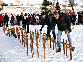 People place crosses for fallen soldiers during a Remembrance Day ceremony at Ainsworth Dyer Memorial Bridge at Rundle Park in Edmonton, Alta., on Monday, Nov. 11, 2013. Codie McLachlan/Edmonton Sun