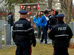 Two Edmonton Police Service constable police watch students from Westlawn Junior High School as they put remembrance day poppies on the graves of veterans during the No Stone Left Alone ceremony at Westlawn Memorial Gardens at 10132 163 St in Edmonton, Alta., on Thursday day Nov 6 , 2014. Tom Braid/Edmonton Sun