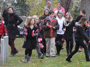 Schoolchildren place Canadian flags on the graves at the military plot in Cataraqui Cemetery prior to a Day of Remembrance service.  MON., NOV 10, 2014 KINGSTON, ONT. MICHAEL LEA THE WHIG STANDARD QMI AGENCY