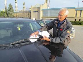 Ed Vanderaa, a resident of Plympton-Wyoming, returned Monday to the Suncor refinery in Sarnia to protest the company's plans to build 46 wind turbines in Lambton County. Vanderaa organized two previous protests at the refinery. Monday, Vanderaa and other protesters placed information on the windshields of cars in the refinery parking lot. (PAUL MORDEN, The Observer)