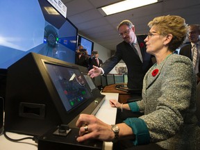 Premier Kathleen Wynne takes a turn on a train simulator instructed by product manager Ian Castle during a tour of Thales’ Canada Toronto office Monday, November 10, 2014. (Dave Abel/Toronto Sun)