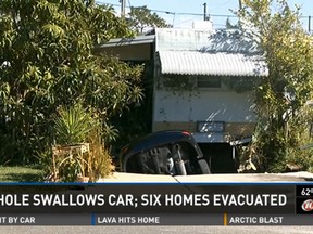 A hole in Florida swallowed a car sitting in a driveway and forced six families to evacuate their homes. (WTSP.com screengrab)