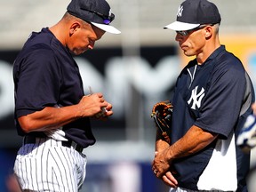 Alex Rodriguez #13 of the New York Yankees autographs a ball as manager Joe Girardi #28 looks on before the start of a MLB baseball game against the Los Angeles Angels of Anaheim at Yankee Stadium on August 14, 2013 in the Bronx borough of New York City. (Rich Schultz/Getty Images/AFP)