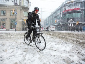 A cyclist makes his way through snow in the intersection of Yonge St. and Dundas Ave. in Toronto March 12, 2014. (Ernest Doroszuk/Toronto Sun)