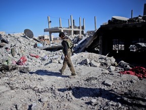 A fighter of the Syrian Kurdish People's Protection Units walks on the battlegrounds following fighting in the Syrian besieged border town of Ain al-Arab, Nov. 7, 2014. (AHMED DEEB/AFP)