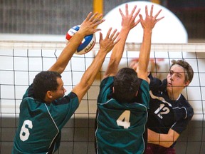 John Paul II?s Jake Price pounds the ball down the block of Julian Black and Jordan Camara of Mother Teresa during their TVRA District Conference AAAA senior boys volleyball final at JPII on Wednesday. The host Jaguars won 3-0. (Mike Hensen/The London Free Press)