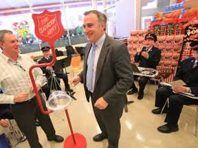 Mayor of Belleville, Ont. Neil Ellis, right, and Wayne Dewe, owner of Dewe’s Independent Grocer, kick off this year's Belleville Salvation Army Kettle Campaign with a donation, while members of the Salvation Army Brass Band perform at the Dundas Street East grocery store Thursday, Nov. 13, 2014.  - JEROME LESSARD/THE INTELLIGENCER/QMI AGENCY