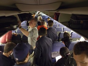 A passenger removes his luggage from an overhead bin on an American Airlines flight after arriving in New York December 10, 2013. Picture taken December 10, 2013.    REUTERS/Carlo Allegri