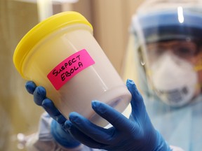 Julie Craig, a senior technologist for point-of-care testing in the laboratory of Belleville General Hospital, holds a container similar to that which held specimens from a suspected Ebola virus patient in Belleville, Ont., on October 30, 2014. (Luke Hendry/QMI Agency)