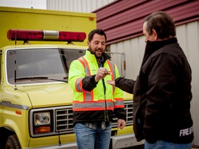 Kyle Meunier, President of the Klondike Trail Search and Rescue Association gives a Loonie to Woodlands County, to make sure that the transfer of ownership for the Fort Assiniboine fire department's old mobile command unit, is legal outside of the Fire Hall in Fort Assiniboine, Alta. on Thursday, Nov. 6. The unit is being donated to the Klondike Trail Search and Rescue association, a volunteer association that acts on behalf of the Alberta fire commissioners office to provide protective services along the Klondike trail near Barrhead and and Woodlands County. 
Adam Dietrich | Whitecourt Star