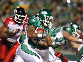 Saskatchewan Roughriders running back Anthony Allen runs the ball while getting chased by Calgary Stampeders defensive lineman Junior Turner during CFL action in Regina October 3, 2014. (REUTERS/David Stobbe)