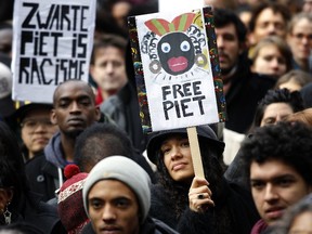 Demonstrators hold signs reading "Black Pete is Rascism" and "Free Black Pete" during a demonstration against Zwarte Piet (Black Pete) in Amsterdam in this Nov. 16, 2013 file photo.  (AFP PHOTO/ANP BAS CZERWINSKI)