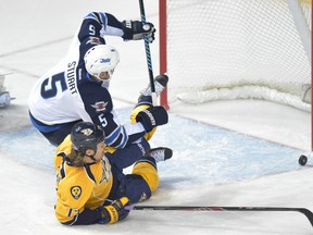 Winnipeg Jets defenceman Mark Stuart and Nashville Predators center Olli Jokinen (13) fight for the puck during the first period at Bridgestone Arena.