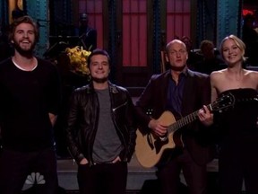 Liam Hemsworth (l), Josh Hutcherson (2nd l) and Jennifer Lawrence (r) help out Woody Harrelson (2nd r) in his opening monologue for "Saturday Night Live." (SCREENSHOT)
