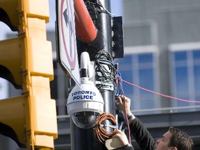 A member of the Toronto Police Video Services Unit tweaks a camera mounted above Yonge and Dundas Square as part of a pilot project. (Toronto Sun files)