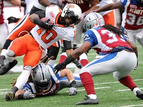 Stefan Logan #10 of the BC Lions runs with the ball from Bear Woods #48 and Jerald Brown #39 of the Montreal Alouettes during their CFL Eastern Division semifinal game at Percival Molson Stadium on November 16, 2014 in Montreal, Quebec, Canada. (Richard Wolowicz/Getty Images/AFP)
