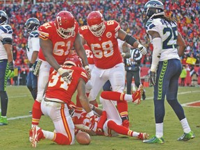 Kansas City Chiefs’ Knile Davis (bottom) is congratulated by teammates after scoring the game-winning touchdown on Sunday. (USA TODAY SPORTS)