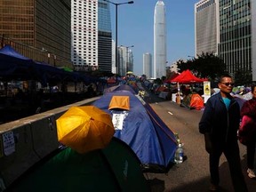 People walk on a main road leading to the financial central district (background), blocked by tents set up by pro-democracy protesters, in Hong Kong November 17, 2014.  .  REUTERS/Bobby Yip