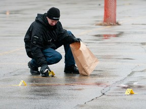 A police investigator gathers evidence at the scene of an overnight shooting in a parking lot at Richmond and Angel streets in London on Tuesday, Dec. 27, 2011. (Free Press file photo)