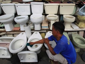 Perso Pacheco cleans a recycled toilet bowl he sells for 1,500 pesos ($34) each along a major street in Manila November 19, 2014. The United Nations General Assembly has declared November 19 as World Toilet Day to raise awareness about the need for all human beings to have access to sanitation.  REUTERS/Romeo Ranoco