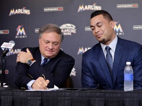 Miami Marlins right fielder Giancarlo Stanton (right) watches as Marlins owner Jeffery Loria signs Stanton's new contract at a press conference at Marlins Park Wednesday. (Steve Mitchell/USA TODAY Sports)