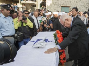 Israeli President Reuven Rivlin (R) pays his respects on the coffin of Israeli police officer Zidan Saief, 30, a member of Israel's Druze minority, during his funeral in his northern home village of Yanuh-Jat, on November 19, 2014. Saief died after suffering severe injuries, bringing the death toll to five, when two Palestinians armed with a gun and meat cleavers burst into the synagogue Nov. 18. (AFP PHOTO/JACK GUEZ)