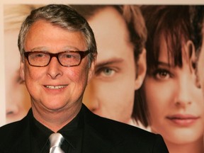 Director Mike Nichols poses next to a poster for his new film "Closer" as he arrives for the film's premiere in Los Angeles in a November 22, 2004 file photo. REUTERS/Fred Prouser/files