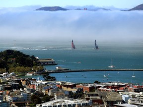 Emirates Team New Zealand races Oracle Team USA in front of the Golden Gate Bridge, mostly obscured by fog, during race 3 of the America's Cup finals on September 8, 2013 in San Francisco, California.  (Jamie Squire/Getty Images/AFP)