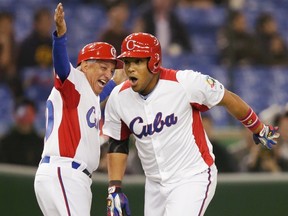 Cuba's Yasmany Tomas (R) celebrates with coach Primitivo Diaz after hitting a three-run homer against Taiwan in the fourth inning at the World Baseball Classic (WBC) second round game in Tokyo March 9, 2013.   (REUTERS/Toru Hanai)