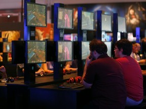 Visitors play the "World of Warcraft: Warlords of Draenor" video game at the Blizzard Entertainment exhibition stand during the Gamescom 2014 fair in Cologne Aug. 13, 2014. REUTERS/Ina Fassbender
