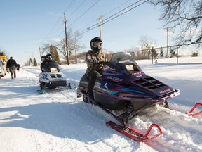 People ride snowmobiles through the streets in Buffalo, New York, November 21, 2014. (REUTERS/Lindsay DeDario)